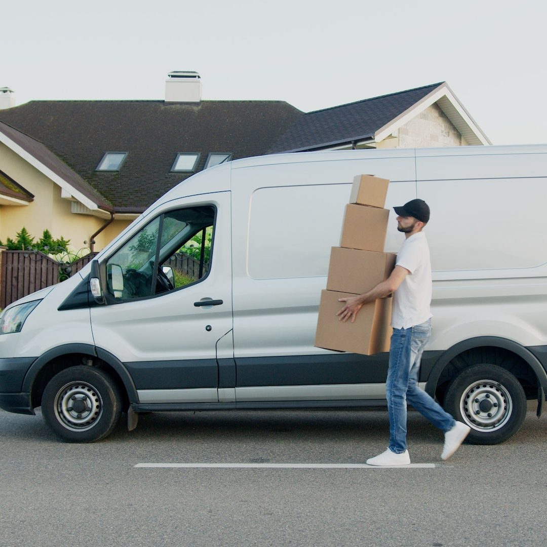 Man Carrying Boxes Beside a Van